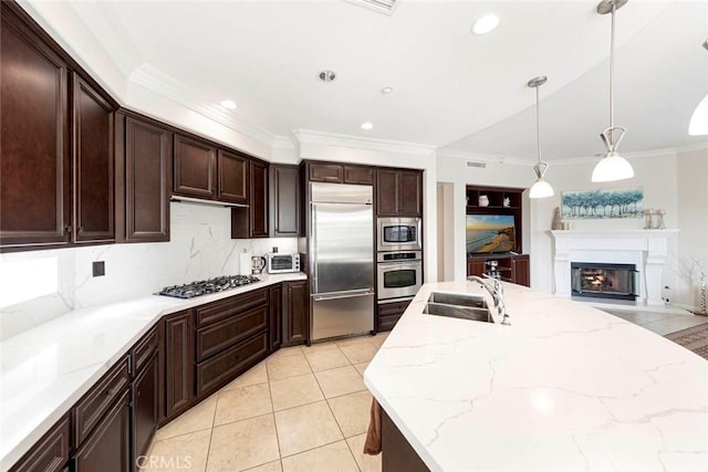 kitchen featuring pendant lighting, ornamental molding, a sink, light tile patterned floors, and built in appliances