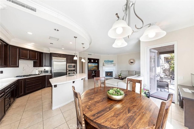 dining space featuring light tile patterned flooring, ornamental molding, visible vents, and a fireplace