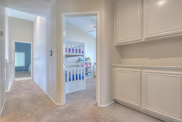 hallway with light carpet and vaulted ceiling