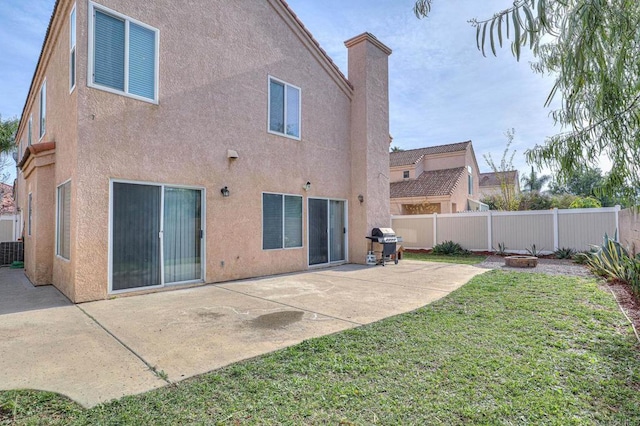 back of property featuring a lawn, cooling unit, and a patio area