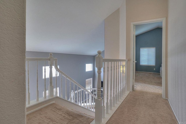 hallway featuring vaulted ceiling and light carpet