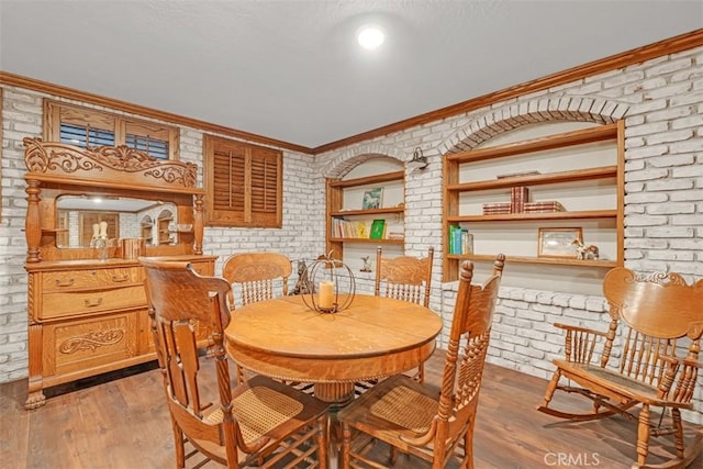 dining space featuring brick wall, light hardwood / wood-style floors, and ornamental molding