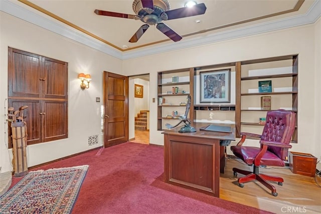 carpeted office space with ceiling fan, built in features, and ornamental molding