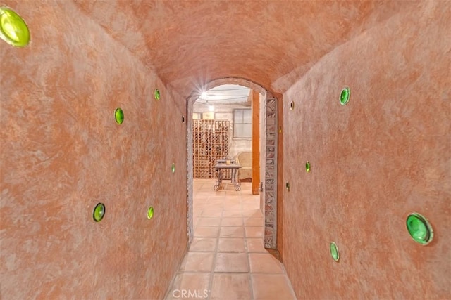 corridor featuring lofted ceiling and light tile patterned floors