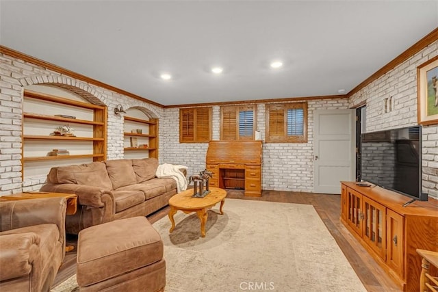 living room featuring brick wall, ornamental molding, and light hardwood / wood-style flooring