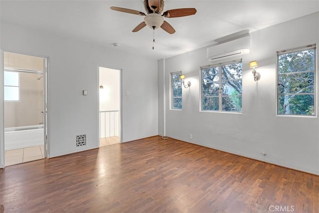 empty room featuring an AC wall unit, hardwood / wood-style floors, and ceiling fan