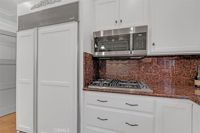 kitchen featuring tasteful backsplash, appliances with stainless steel finishes, dark stone counters, and white cabinetry