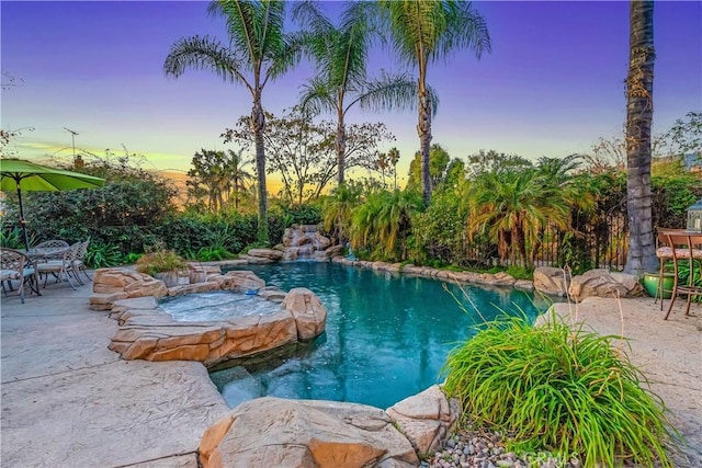 pool at dusk featuring a patio