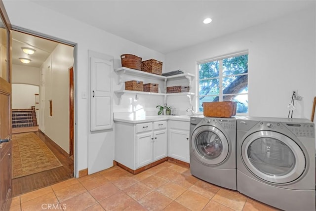 clothes washing area with light tile patterned floors, sink, independent washer and dryer, and cabinets