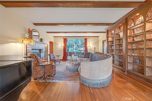 living room with beam ceiling, wood-type flooring, and built in shelves