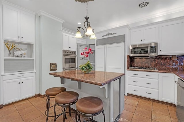 kitchen with decorative light fixtures, white cabinets, light tile patterned floors, and stainless steel appliances