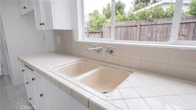 kitchen with sink, white cabinetry, tile counters, and tasteful backsplash