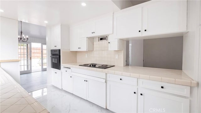 kitchen with white cabinetry, tile countertops, pendant lighting, and black oven