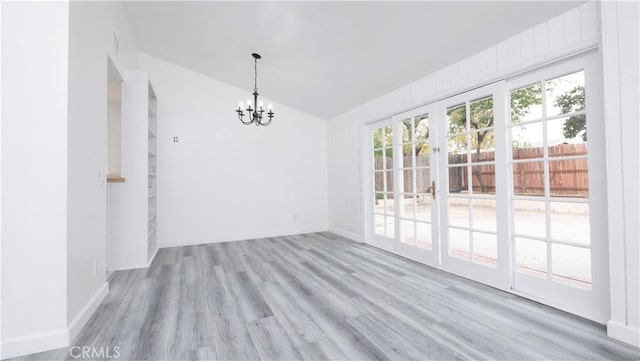 unfurnished dining area featuring light wood-type flooring, a notable chandelier, and vaulted ceiling