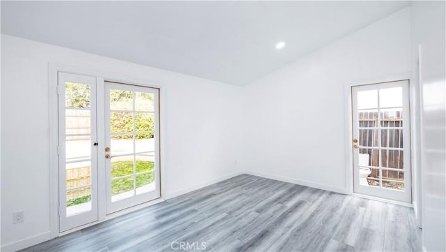 spare room featuring light wood-type flooring and lofted ceiling