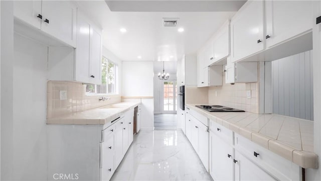 kitchen featuring white cabinetry, tile countertops, black oven, backsplash, and sink