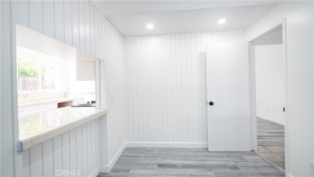 hallway featuring light hardwood / wood-style floors and wooden walls