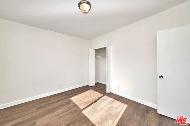 unfurnished bedroom featuring a closet and dark hardwood / wood-style flooring