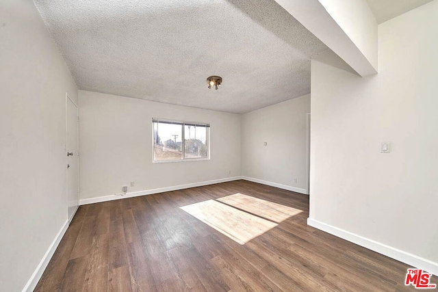 empty room featuring dark hardwood / wood-style floors and a textured ceiling