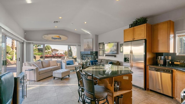 kitchen with light tile patterned floors, a kitchen bar, stainless steel appliances, lofted ceiling, and a center island