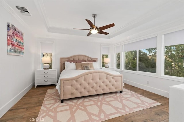 bedroom with ceiling fan, hardwood / wood-style flooring, and a tray ceiling