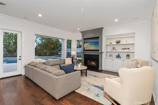 living room with a fireplace, built in features, dark hardwood / wood-style floors, and crown molding