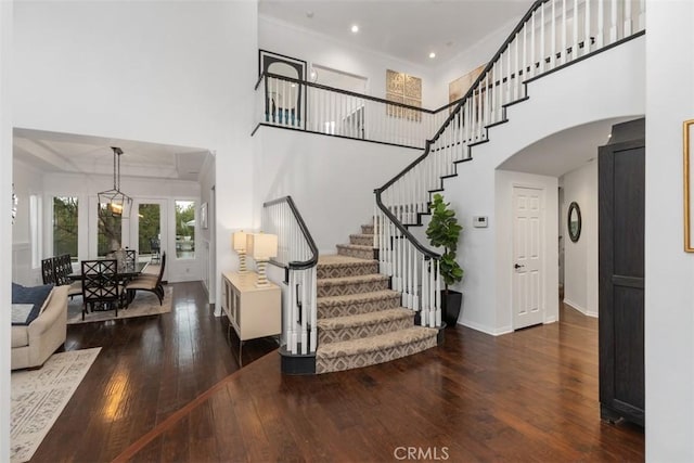 staircase with hardwood / wood-style flooring, ornamental molding, and a towering ceiling