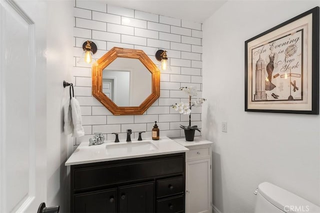 bathroom featuring toilet, vanity, and tasteful backsplash