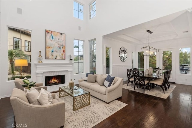 living room with a high ceiling, hardwood / wood-style flooring, a raised ceiling, and an inviting chandelier