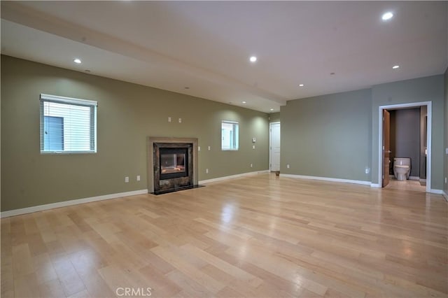 unfurnished living room featuring plenty of natural light, light wood-type flooring, and a fireplace