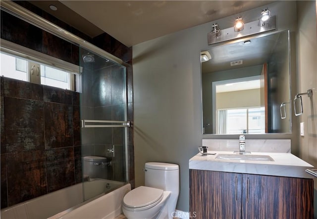 full bathroom with toilet, combined bath / shower with glass door, a wealth of natural light, and vanity