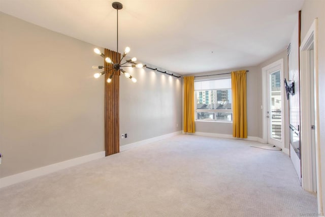 carpeted empty room featuring an inviting chandelier