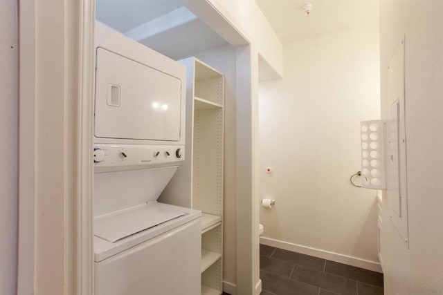 clothes washing area with stacked washer and dryer and dark tile patterned floors