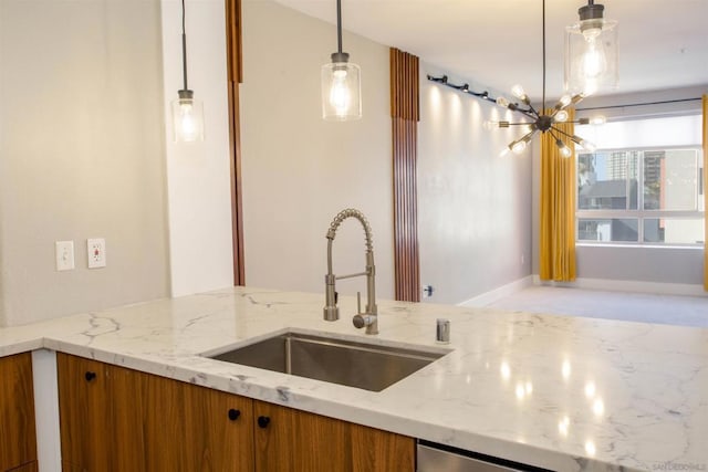 kitchen with hanging light fixtures, an inviting chandelier, sink, and light stone counters