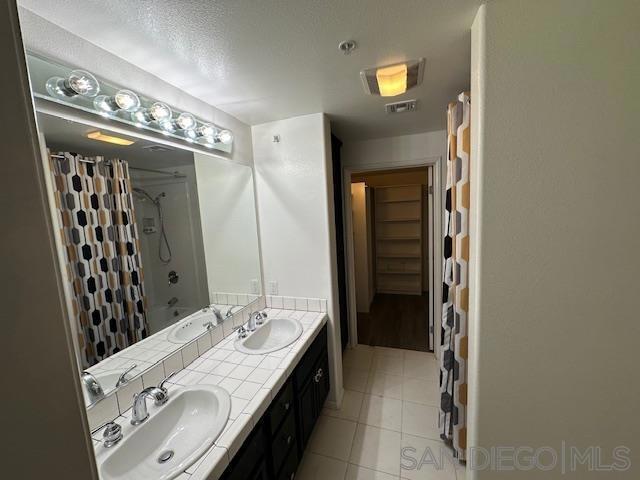 bathroom with vanity, a textured ceiling, and shower / bathtub combination with curtain