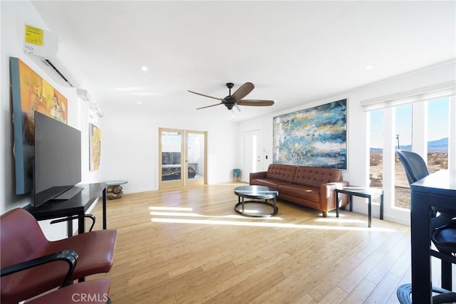 living room featuring ceiling fan, light hardwood / wood-style floors, and an AC wall unit