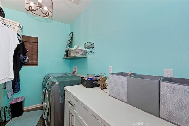 washroom with a notable chandelier, washer and dryer, and cabinets