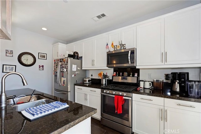 kitchen with sink, white cabinets, stainless steel appliances, and dark stone countertops