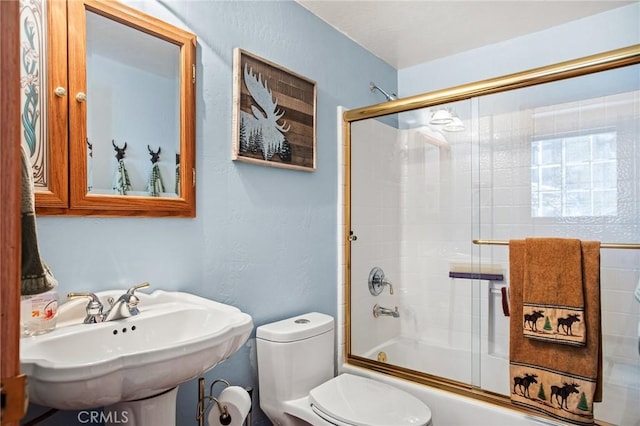 full bathroom with sink, toilet, and combined bath / shower with glass door