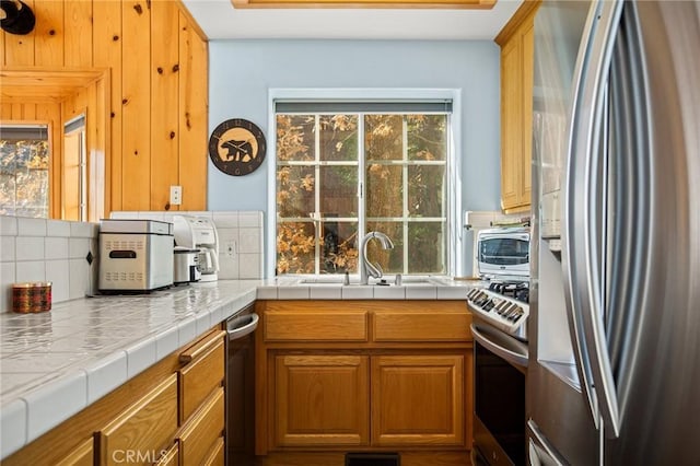 kitchen featuring sink, a wealth of natural light, tile countertops, and appliances with stainless steel finishes