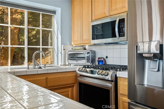 2477 Spring Oak Dr, Running Springs, CA 92382 - kitchen featuring stainless steel appliances, tile countertops, a sink, and backsplash