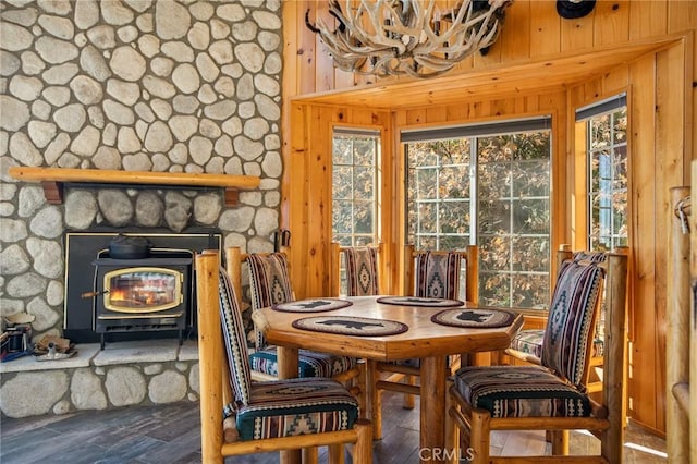 dining area with dark wood-type flooring, wooden walls, and a wood stove