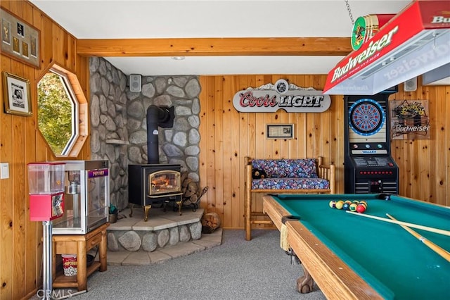 recreation room featuring beamed ceiling, wooden walls, carpet flooring, and a wood stove