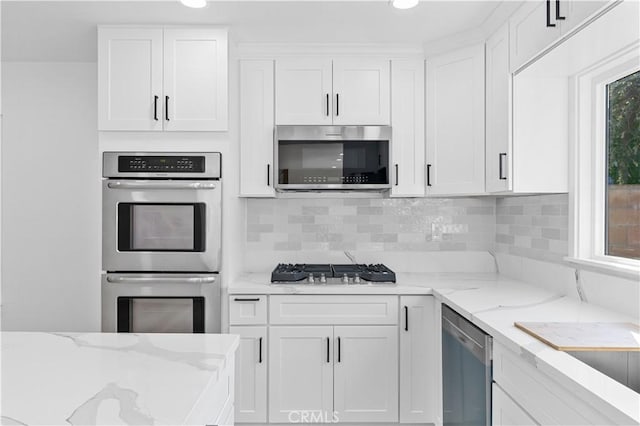 kitchen featuring tasteful backsplash, appliances with stainless steel finishes, light stone counters, and white cabinetry