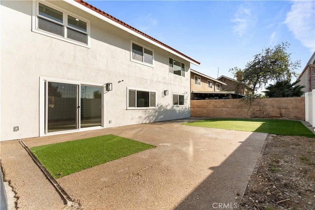 back of house featuring a lawn and a patio