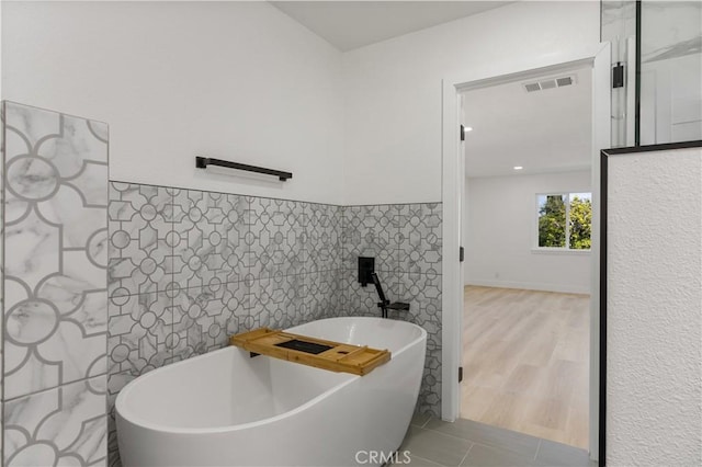 bathroom featuring tile walls, tile patterned floors, and a washtub