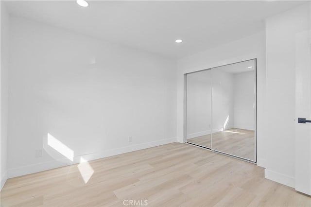 unfurnished bedroom featuring a closet and light wood-type flooring