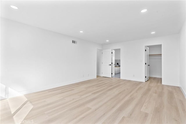 unfurnished bedroom with a closet, a walk in closet, and light wood-type flooring