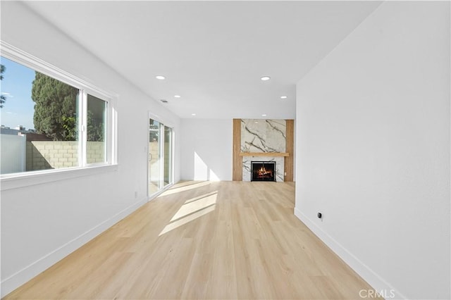 unfurnished living room featuring a high end fireplace and light hardwood / wood-style flooring