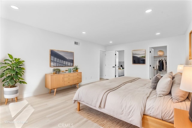 bedroom featuring a closet, a spacious closet, and light hardwood / wood-style flooring